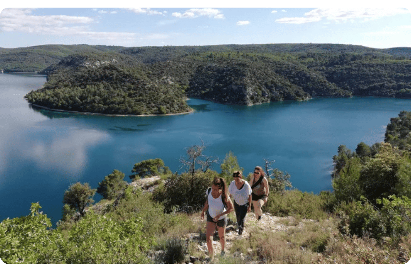 Où faire une retraite yoga en France ? 5 Trois femmes en randonnée sur les hauteurs d'un lac provençal lors d'une retraite jeûne et yoga en France