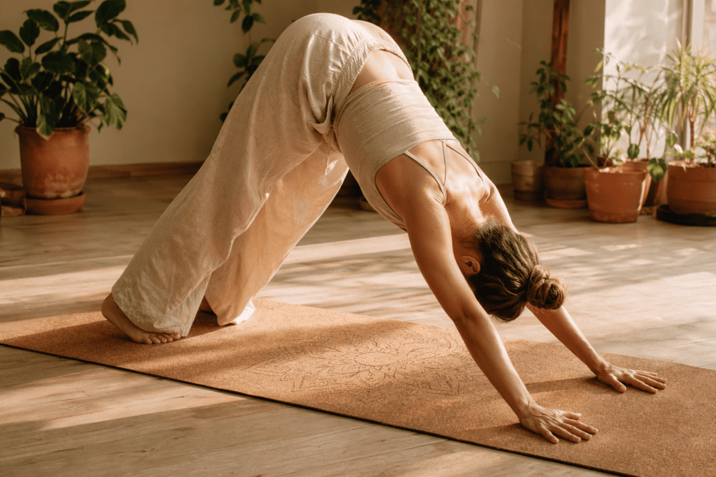 Femme en posture du chien tête en bas sur tapis yoga en liège, lumière dorée studio bois — tapis de yoga en liège
