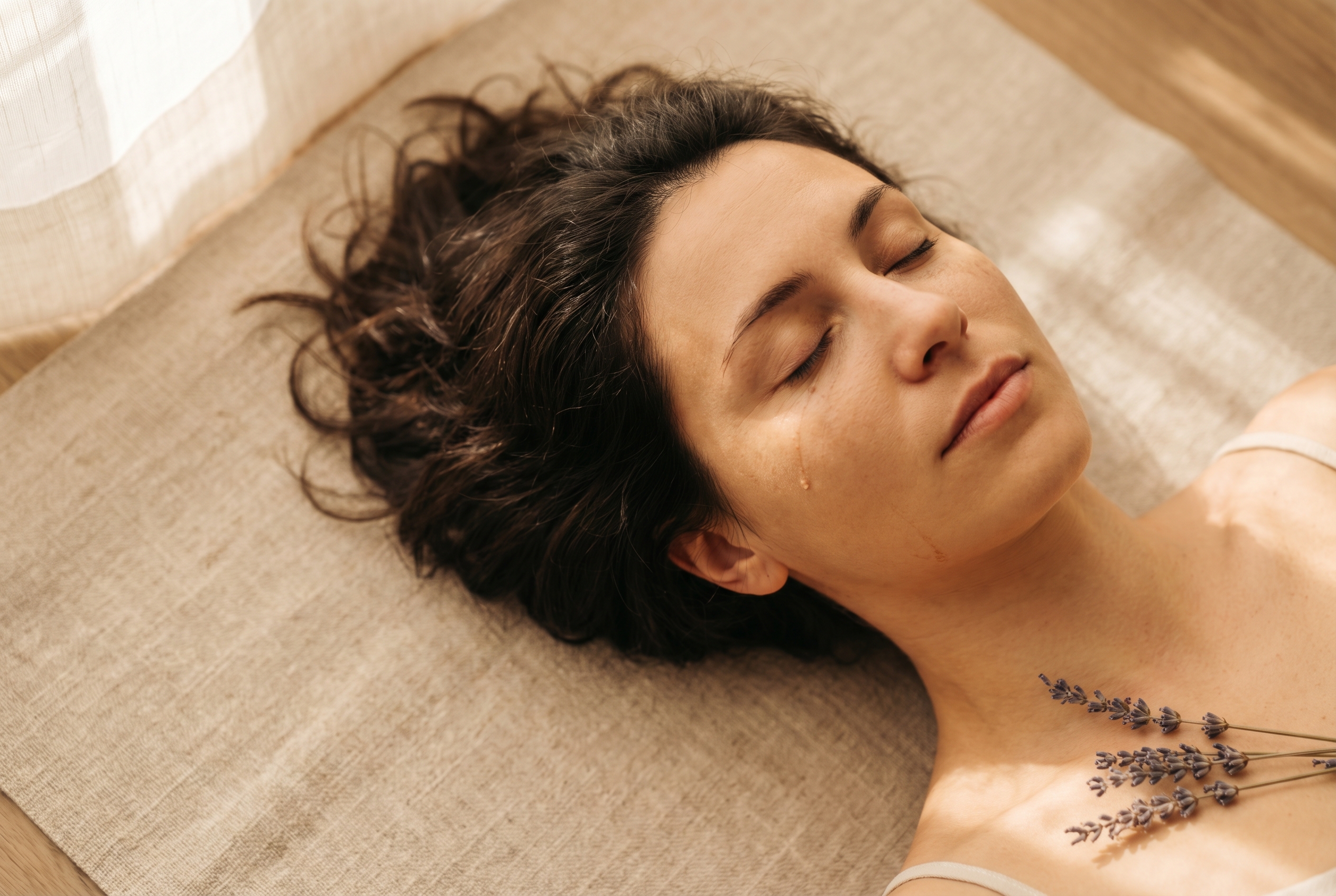 Qu'est-ce que le yin yoga ? 2 Femme allongée en savasana de yin yoga, visage apaisé, brin de lavande séchée à ses côtés, lumière dorée