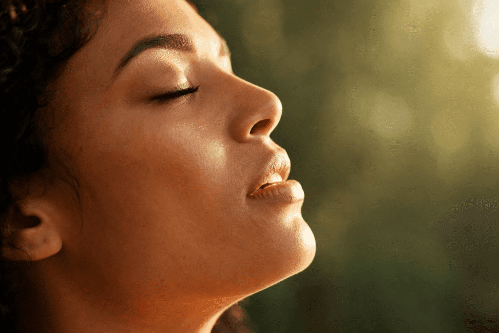 Visage de femme de profil, expiration lente, lumière dorée rasante, soulagement profond, respiration gestion stress
