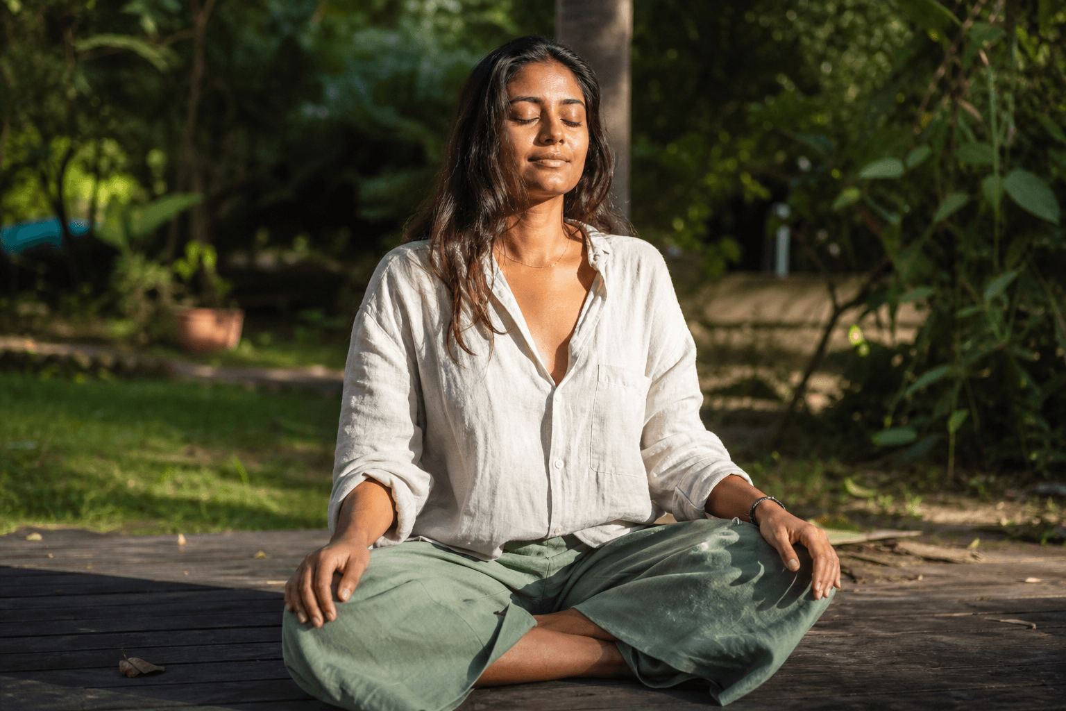 Chakra couronne : 5 signes de blocage et comment l'équilibrer 2 Femme assise en méditation en plein air, lumière dorée naturelle, postures yoga chakra couronne Sahasrara